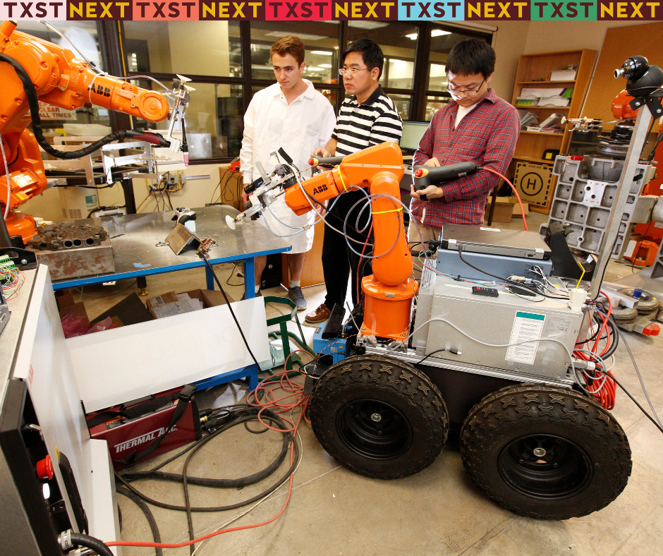 Three manufacturing engineering students working with robotics in a state-of-the-art laboratory inside the Ingram School of Engineering.
