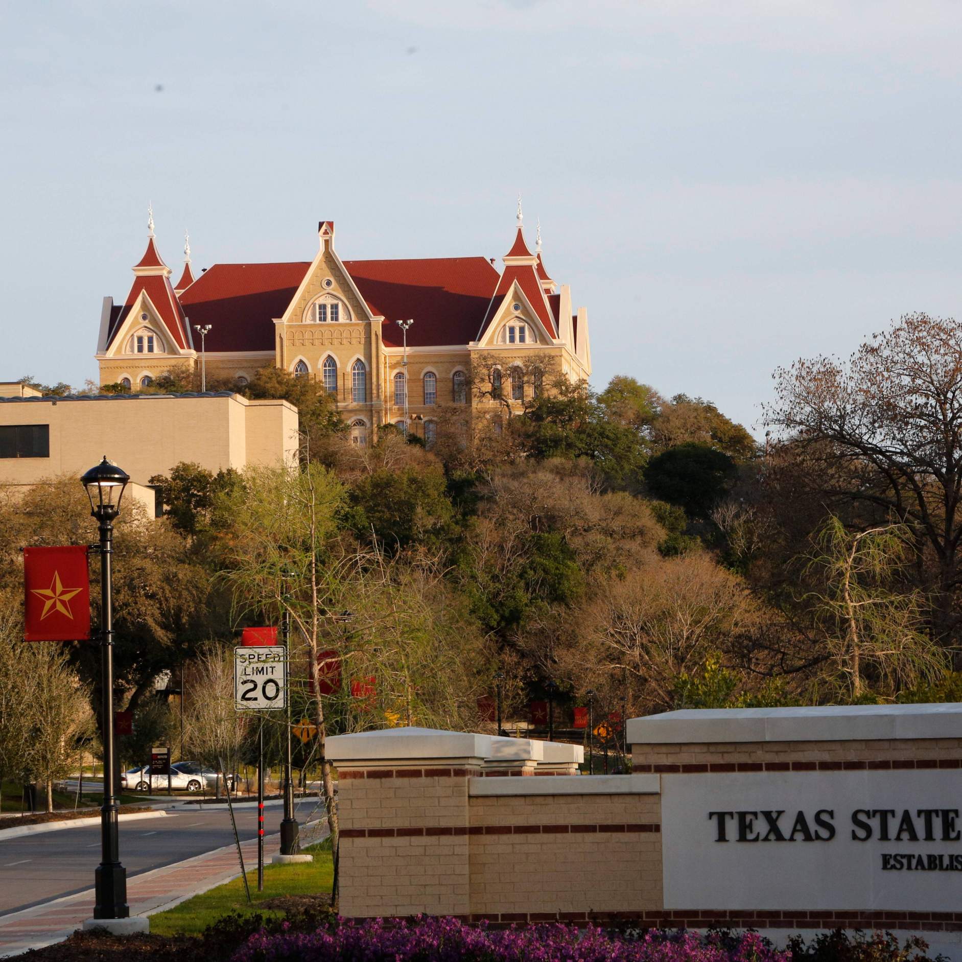 old main with the texas state university sign in front of it