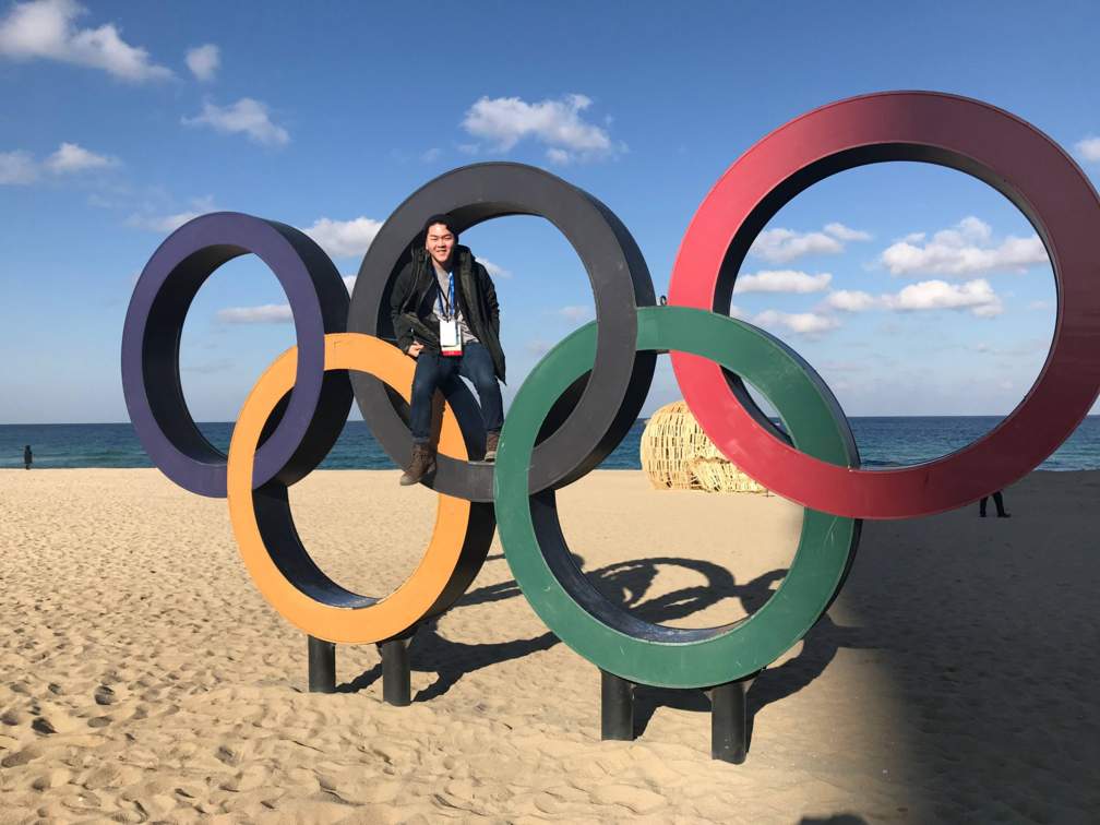 John Lee in front of the Olympic rings on a beach