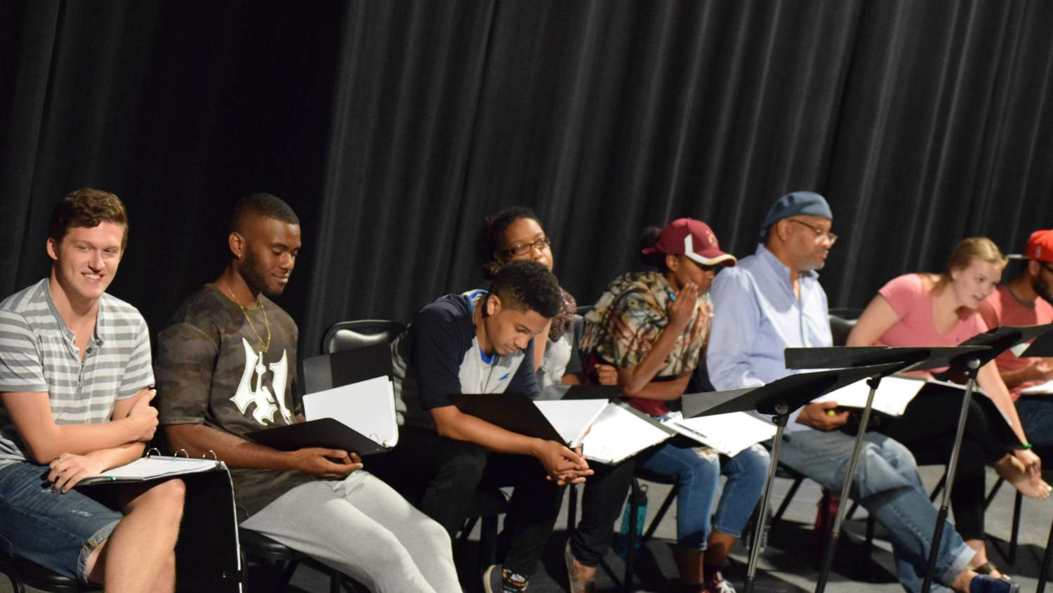 Student actors on stage reviewing the script.
