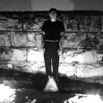 Student work: dark black and white image of a figure in front of a stone wall