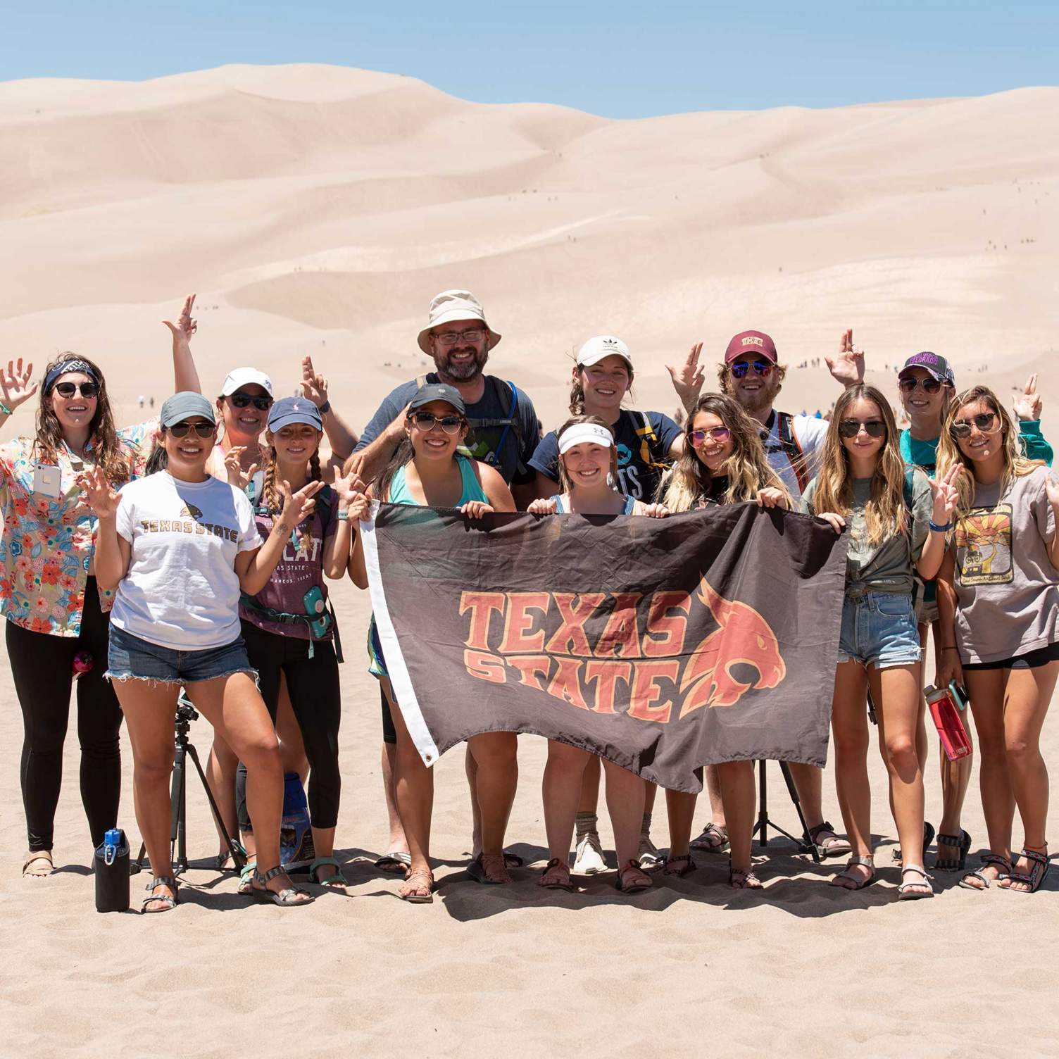 The group poses in front of the sand dunes