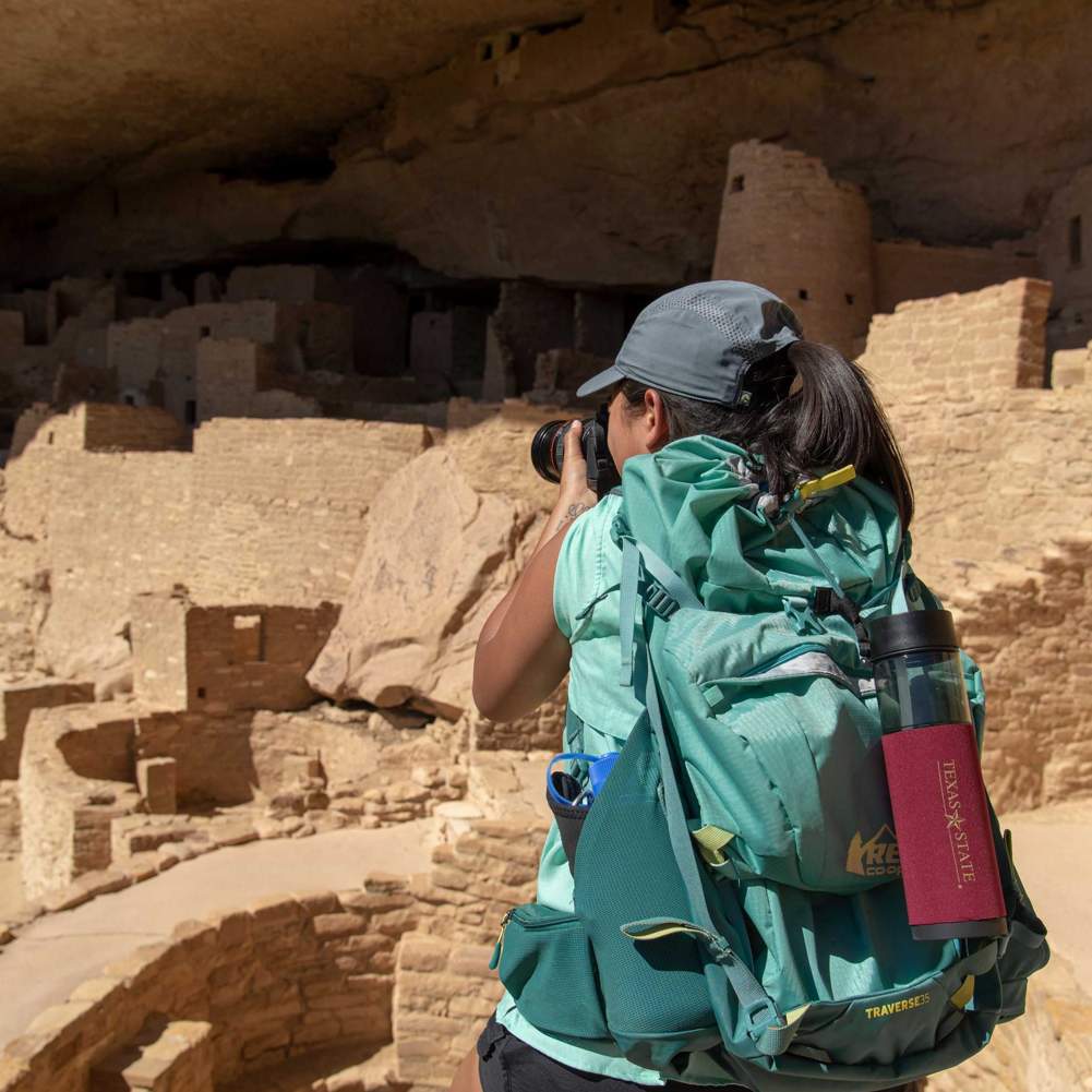 The back of a student as they photograph Cliff Palace