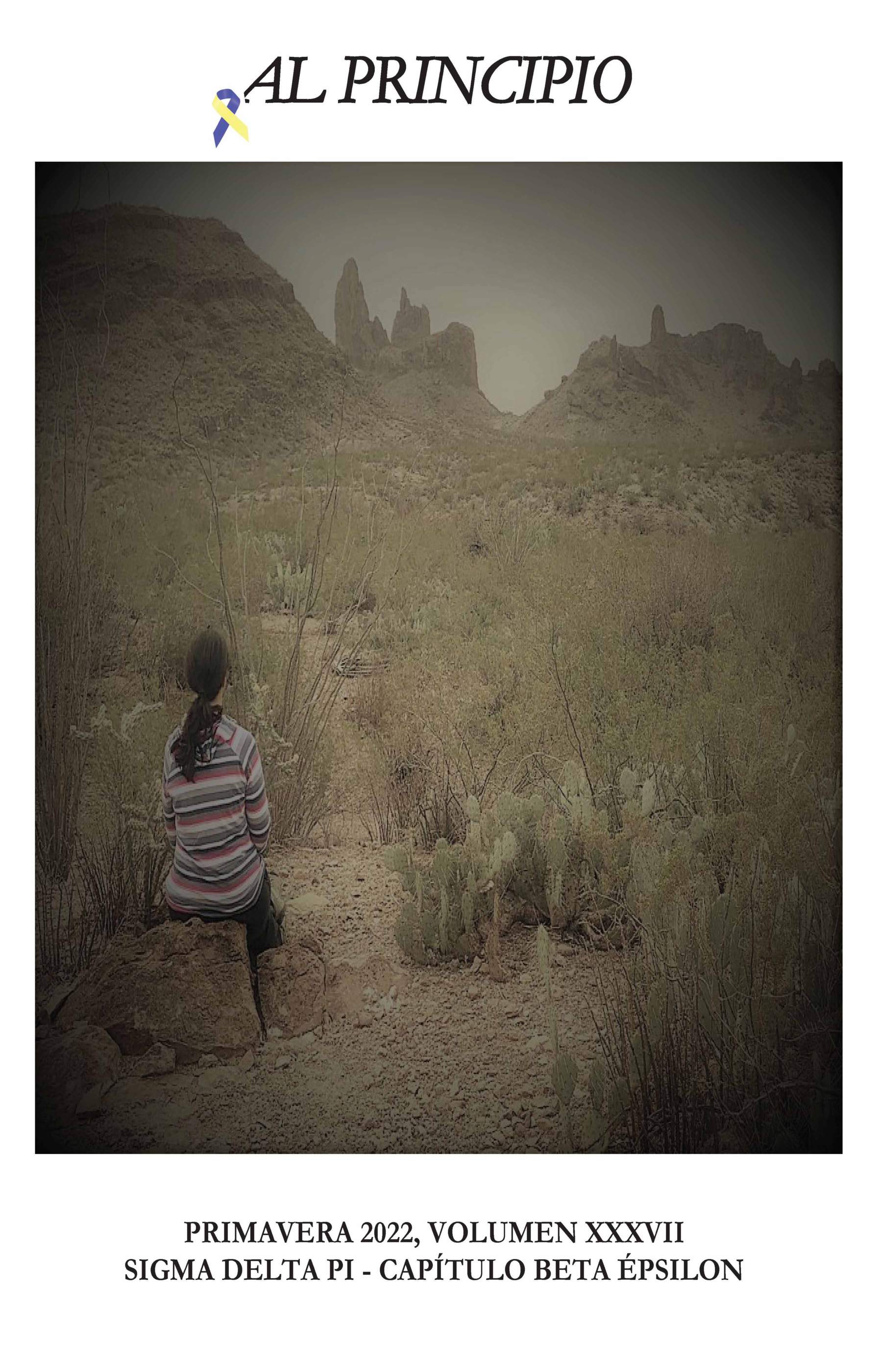 Photo of a woman wearing a striped shirt sitting on a rock in an arid landscape. Text: Al Principio. Primavera 2022, Volumen XXXVII. Sigma Delta Pi - Capítulo Beta Épsilon.