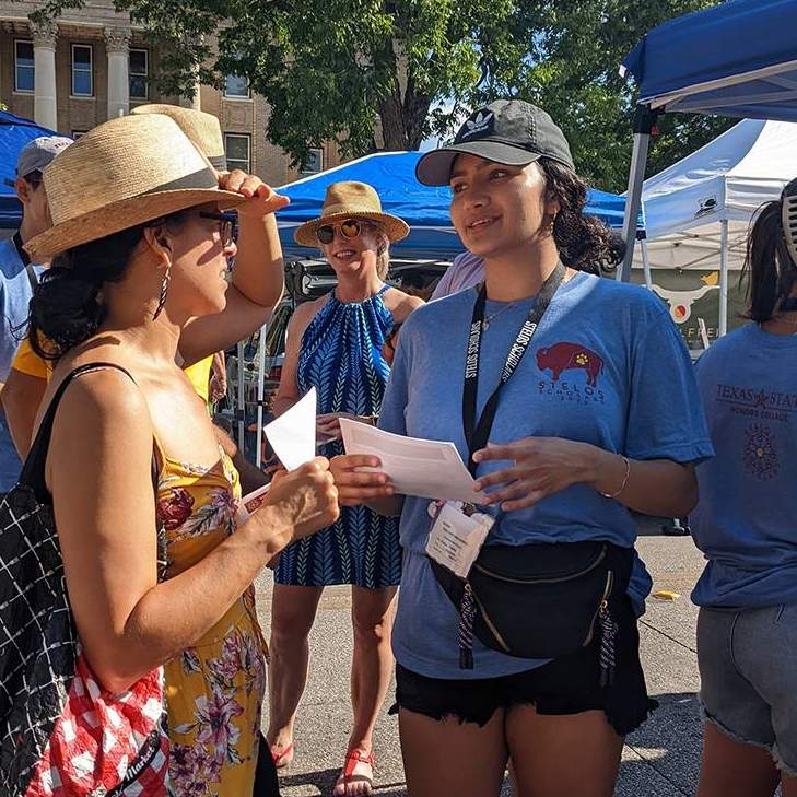 female student speaking with woman at farmers market