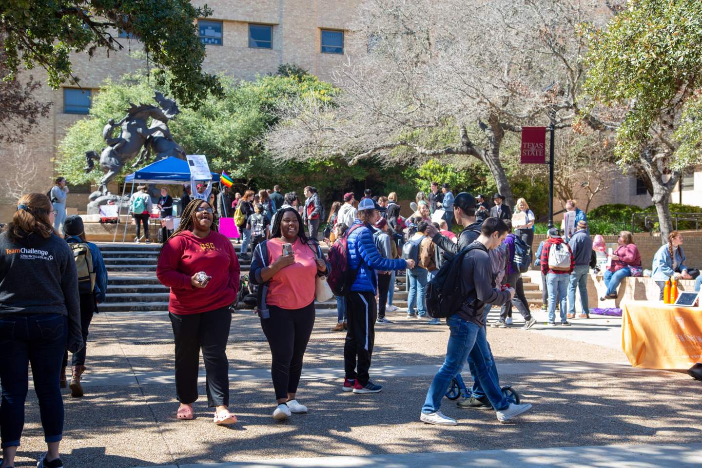 students walking in the quad area on campus near the stallions