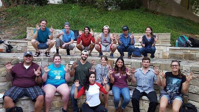 Students making the texas state hand signs in an outdoor classroom, smiling