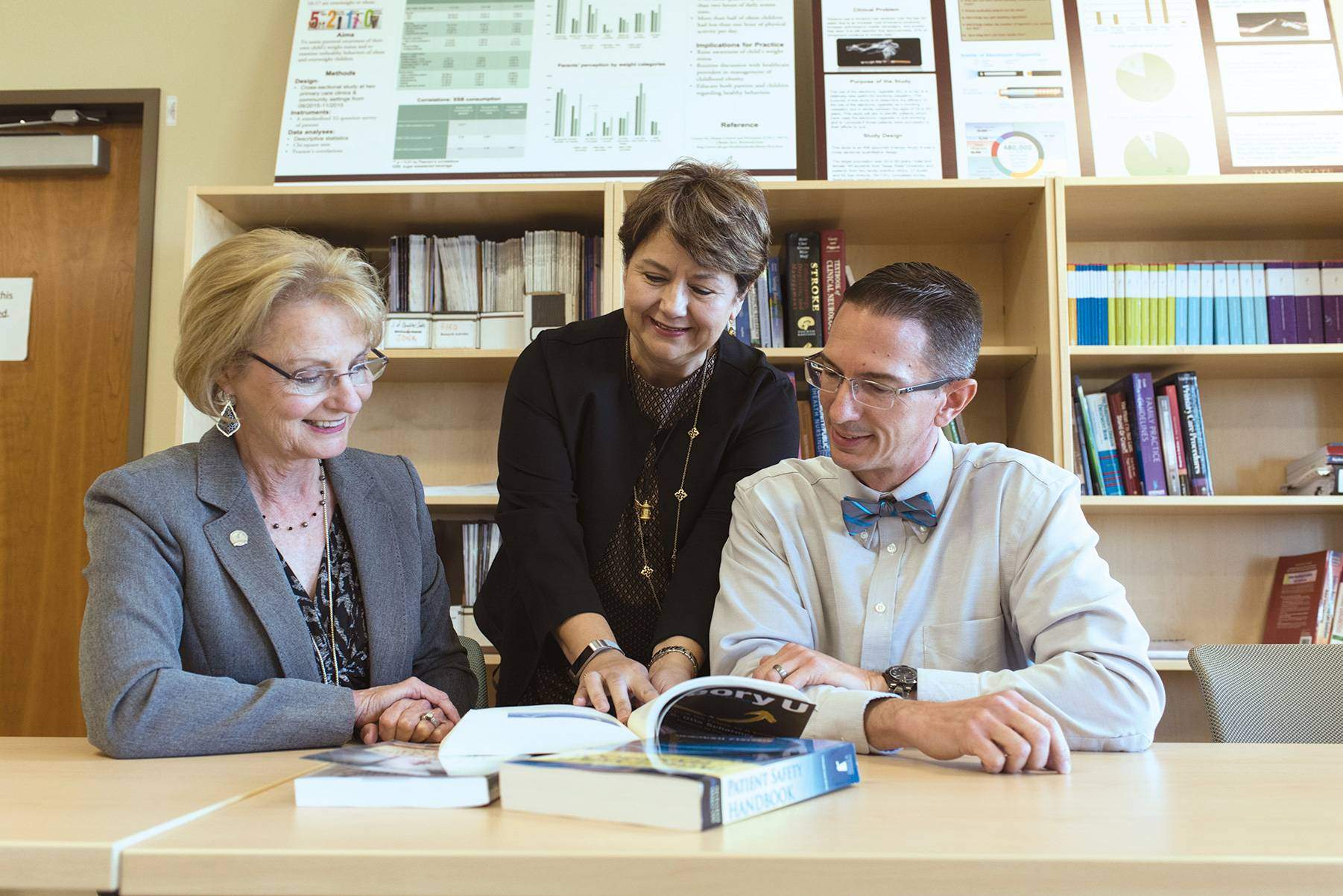 adults going over a part in a book at a desk
