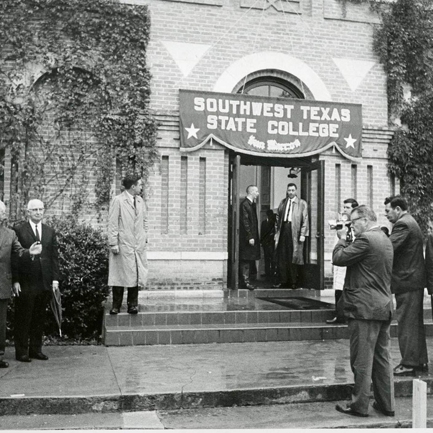 lbj standing in front of swt sign