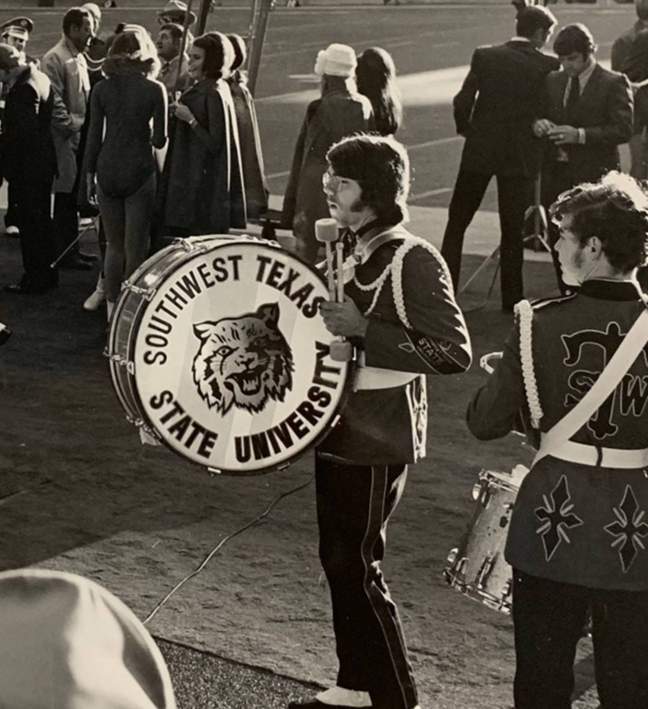 student from 70s carrying bass drum