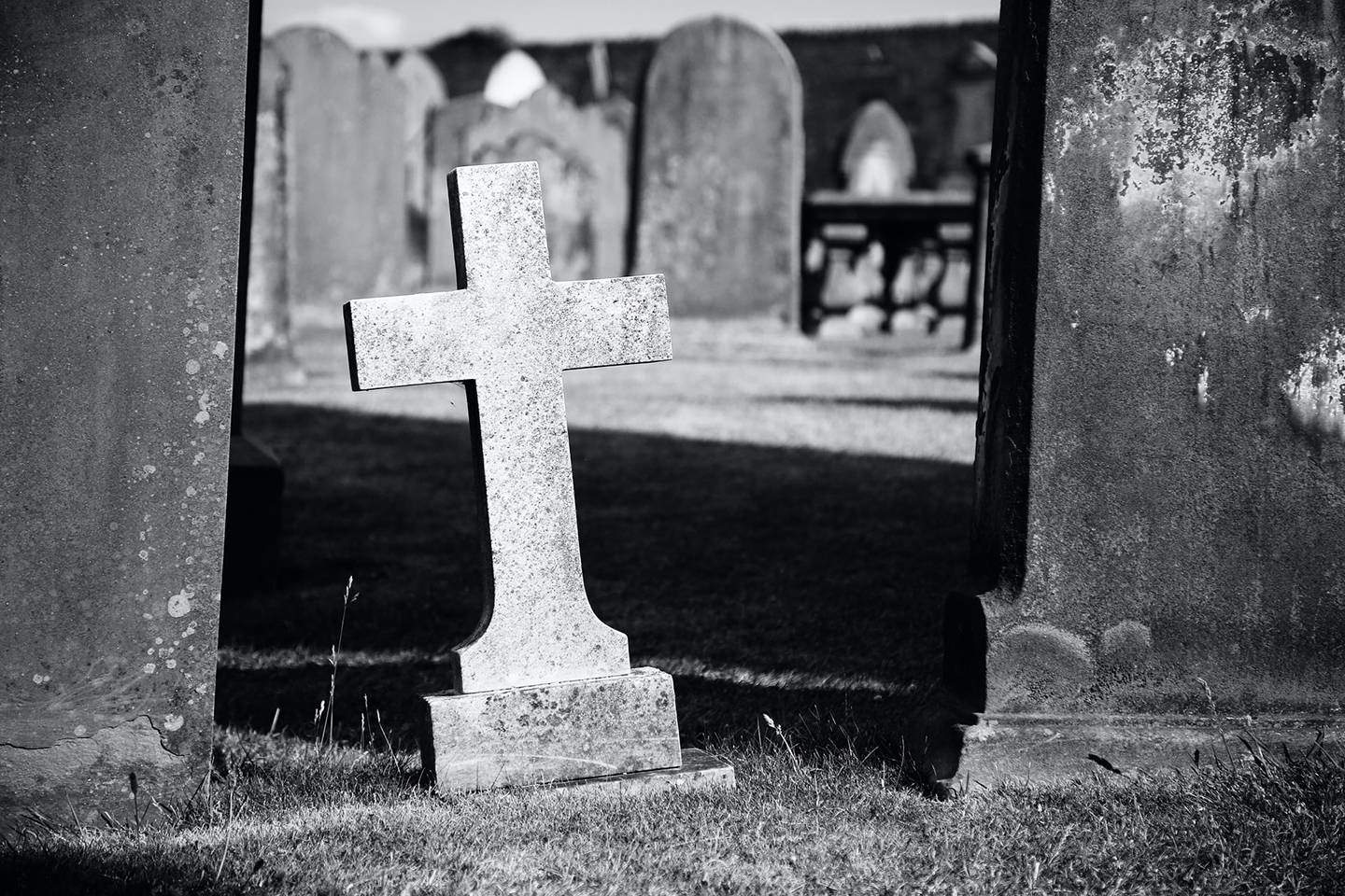 black and white photo of cross in graveyard