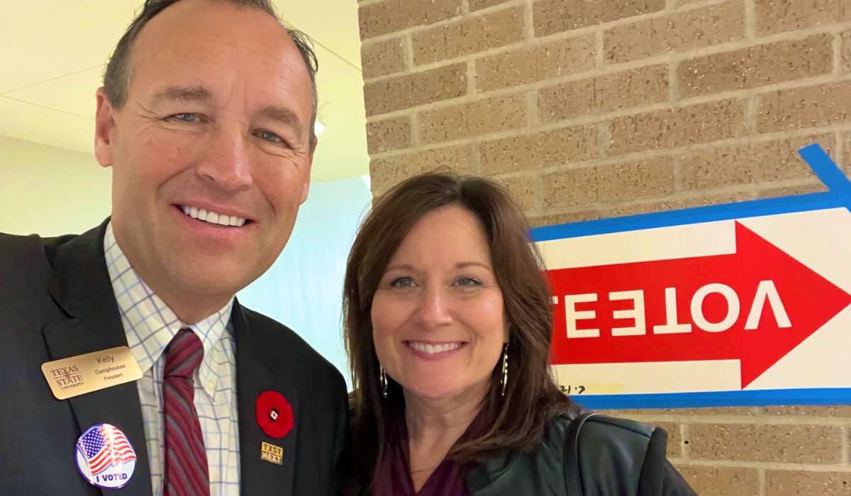 President Damphousse smiling with Beth Damphousse in front of voting sign