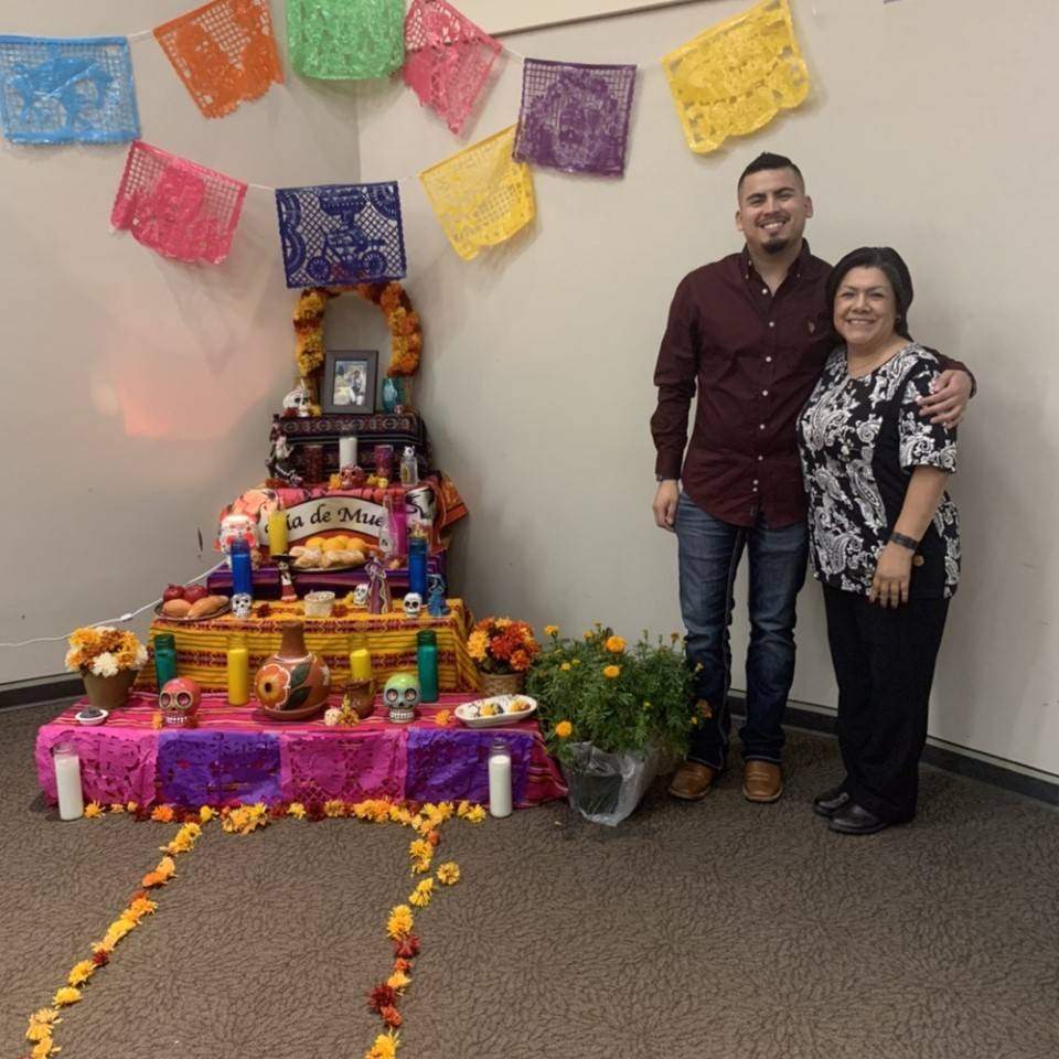 Two people standing next to a Day of the Dead altar