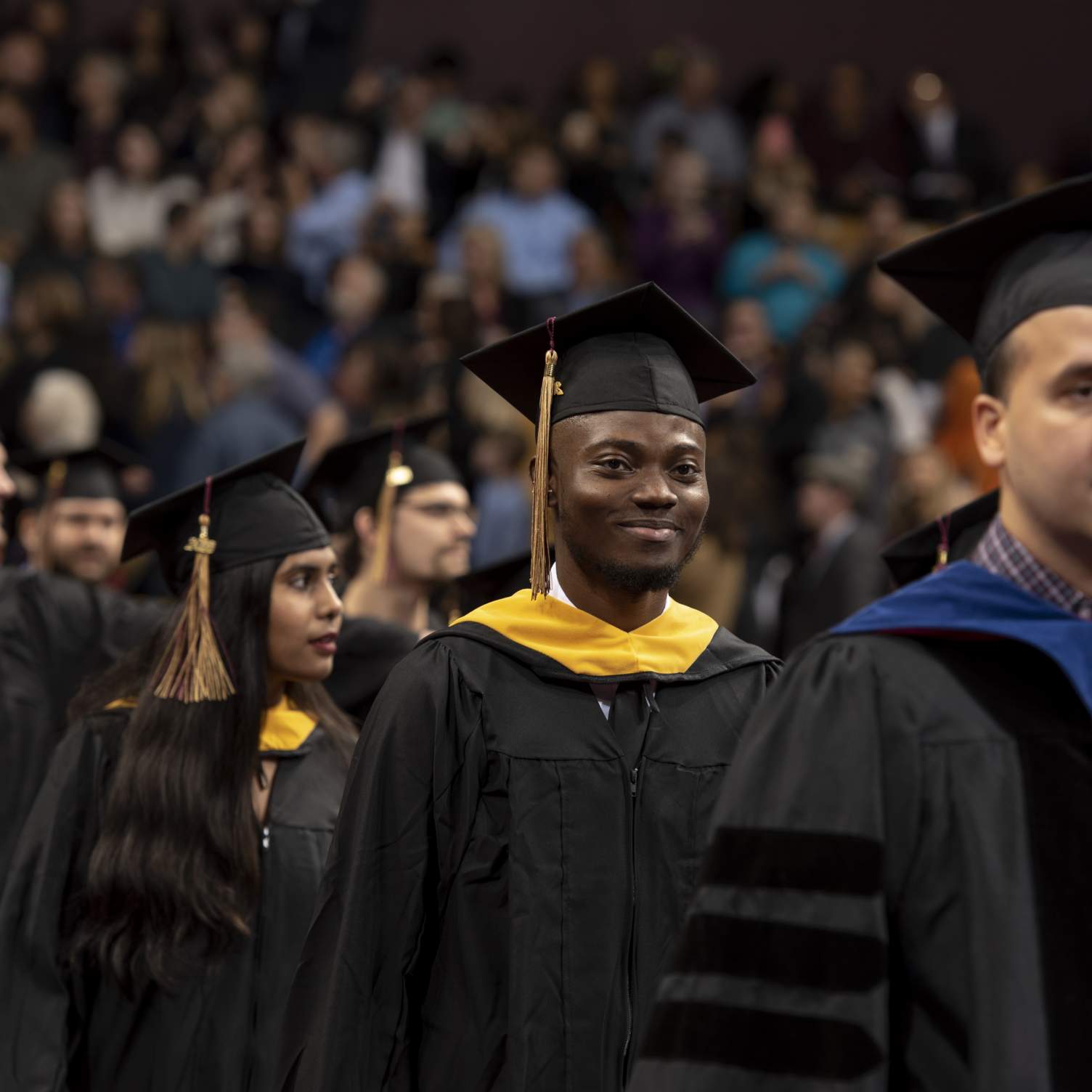 Master's graduates smiling, walking down aisle