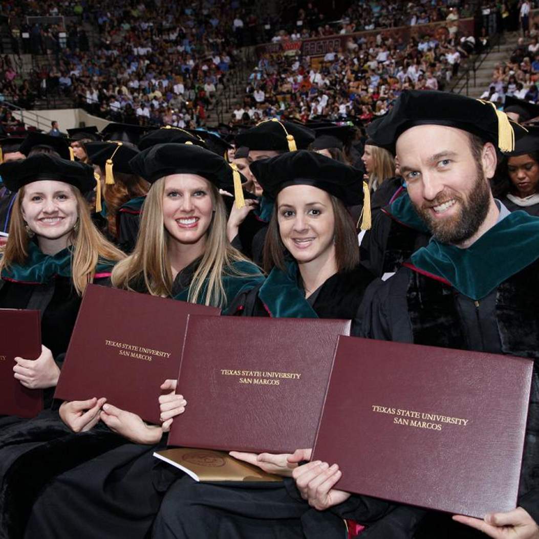 Hooded doctoral candidates with diplomas 