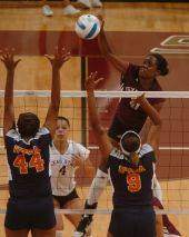 Tx State woman volleyball player spiking ball over two defenders
