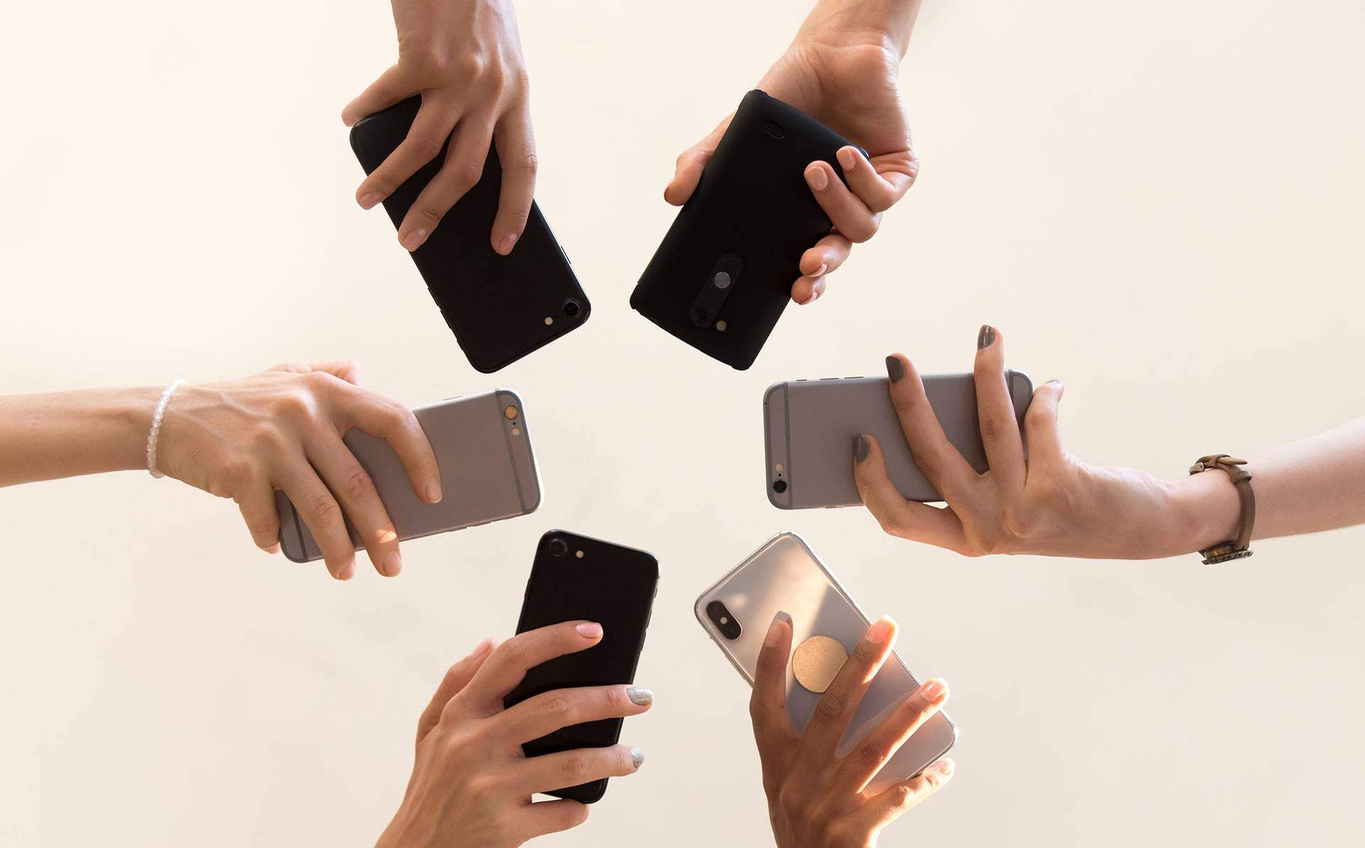 multiple hands hold mobile phones