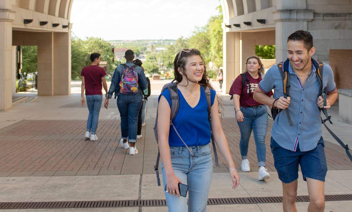 students outside walking to class while smiling