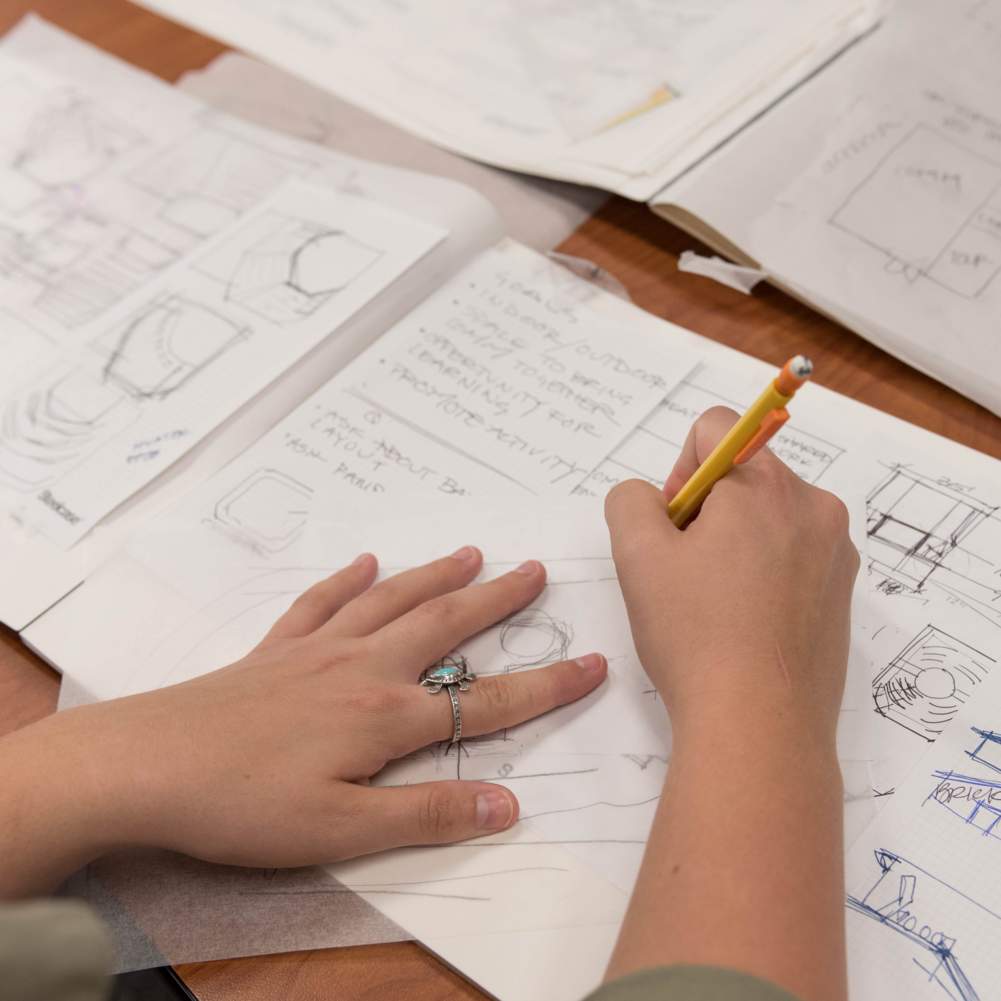 we see hands up close sketching out furniture designs