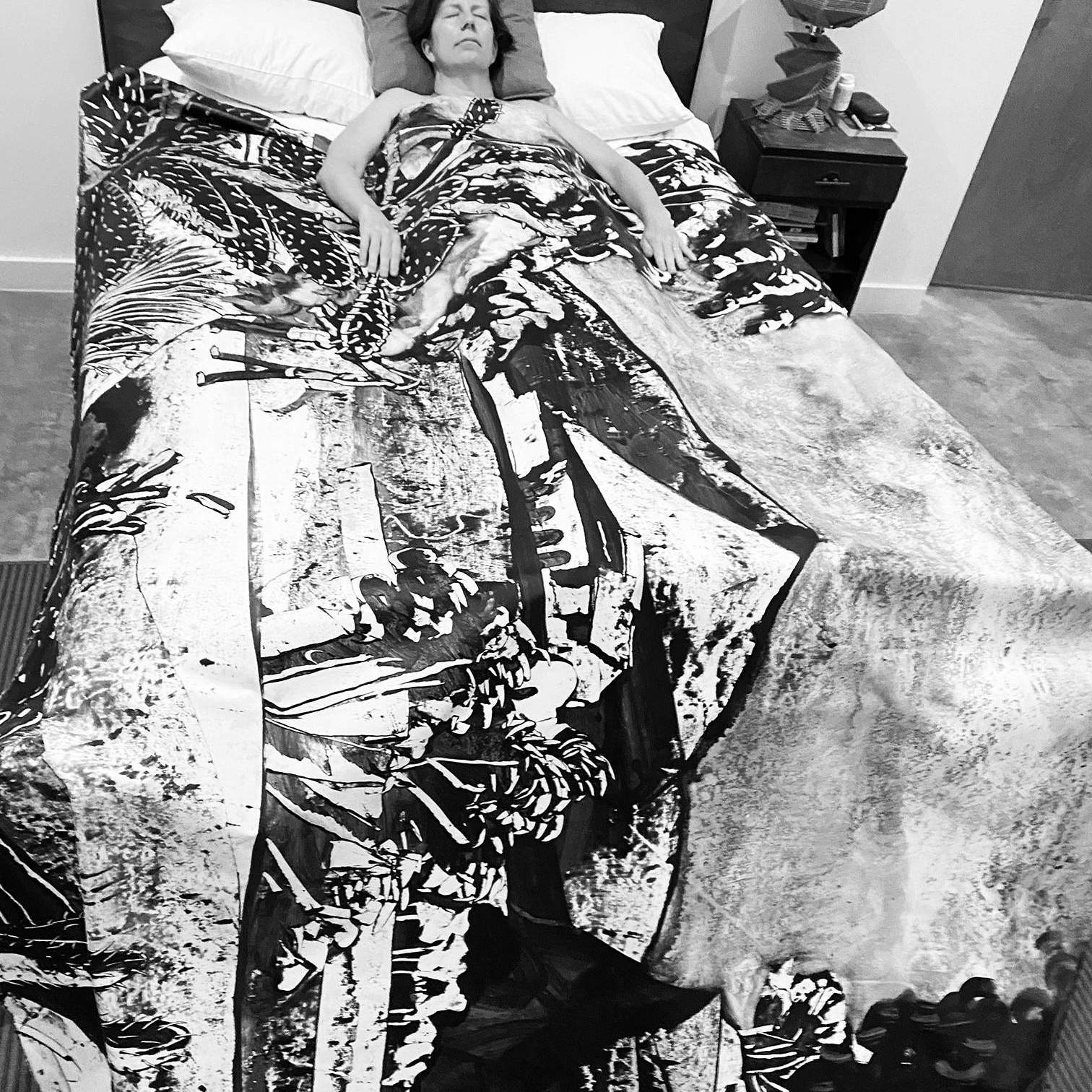 artist laying in bed with painted bed spread