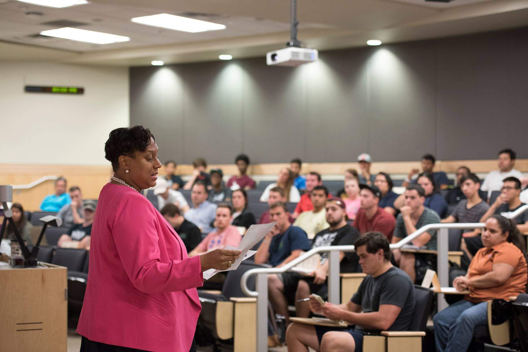 photo of a woman lecturing a large number of students in an large lecture hall