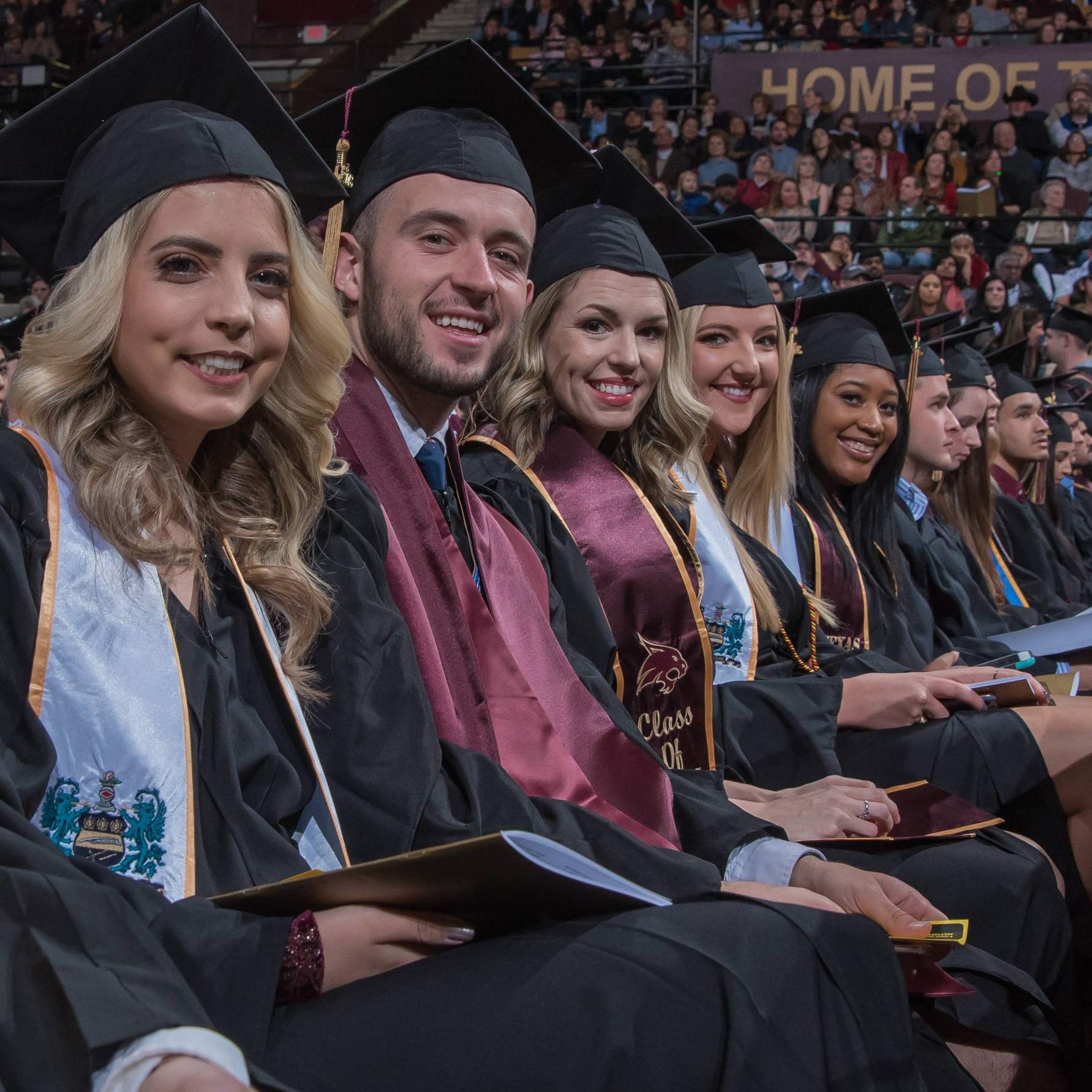 graduates smiling, seated on floor