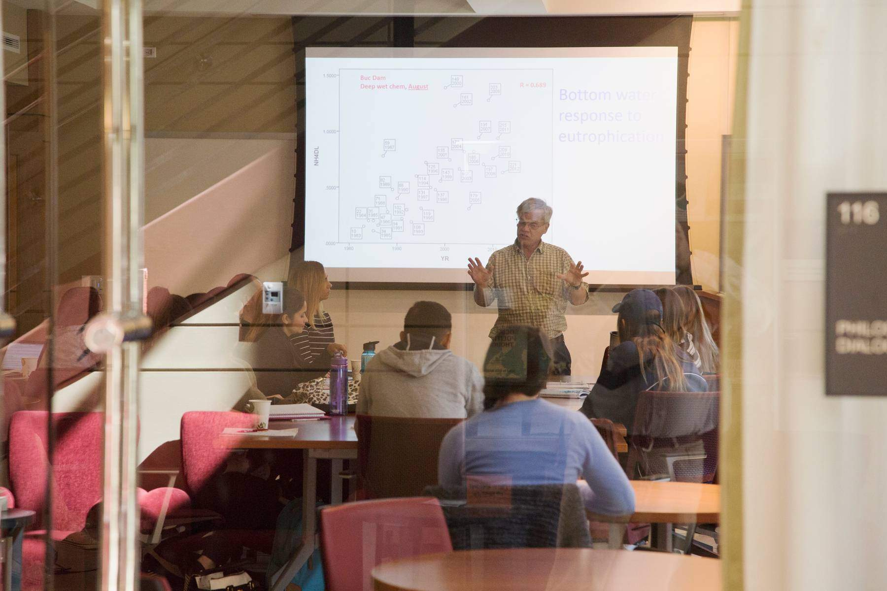 photo of a lecture-style classroom with multiple students listening to an instructor