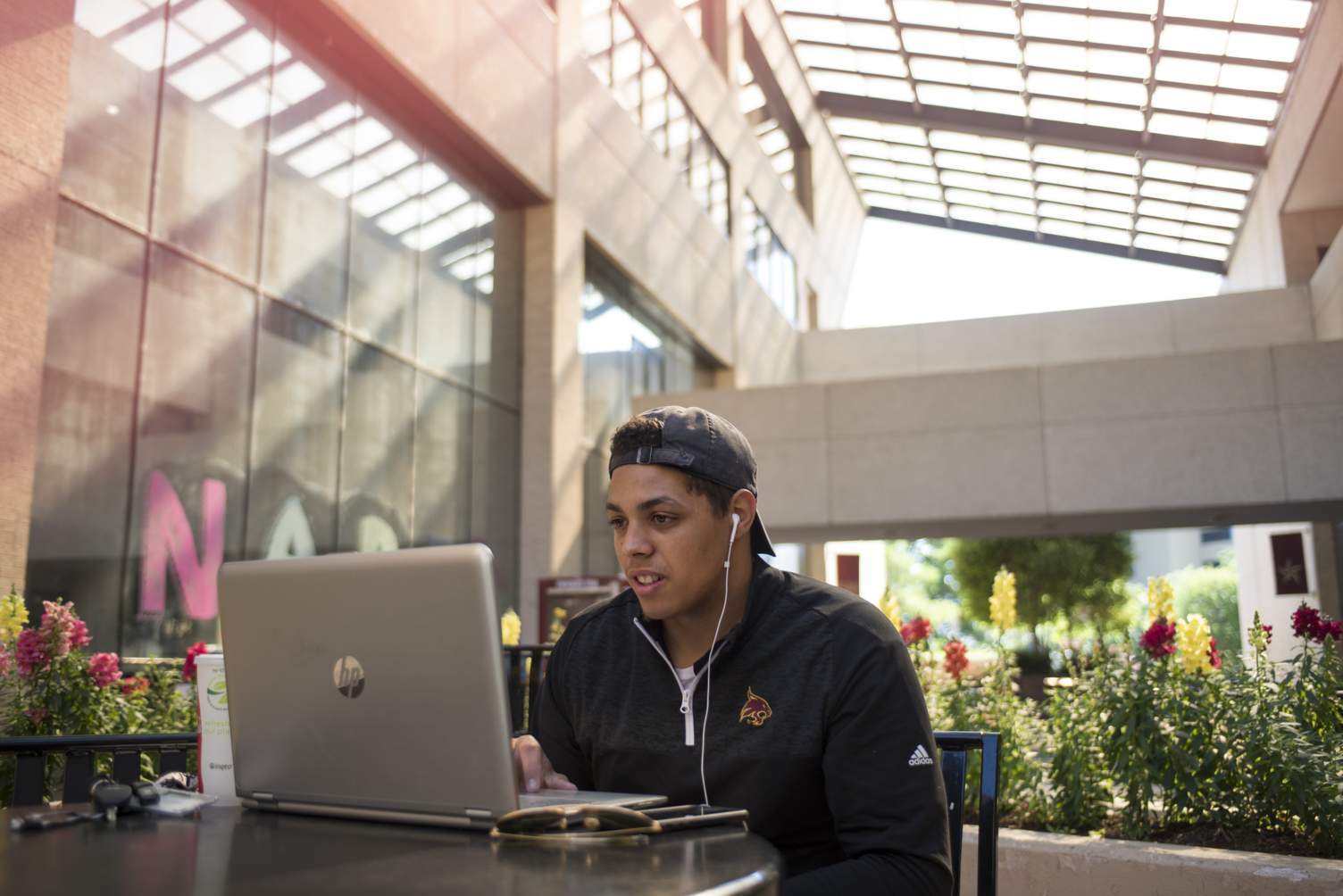 male student looking at laptop while sitting outside