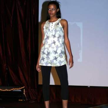 Student wearing a sleeveless long white blouse with a Fleur-de-lis print, Capri leggings and high-heels.