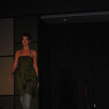 Student/model wearing long spaghetti-strap top with jeans walking down the runway.