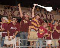 Fans cheering and waving towels at a Bobcat football game