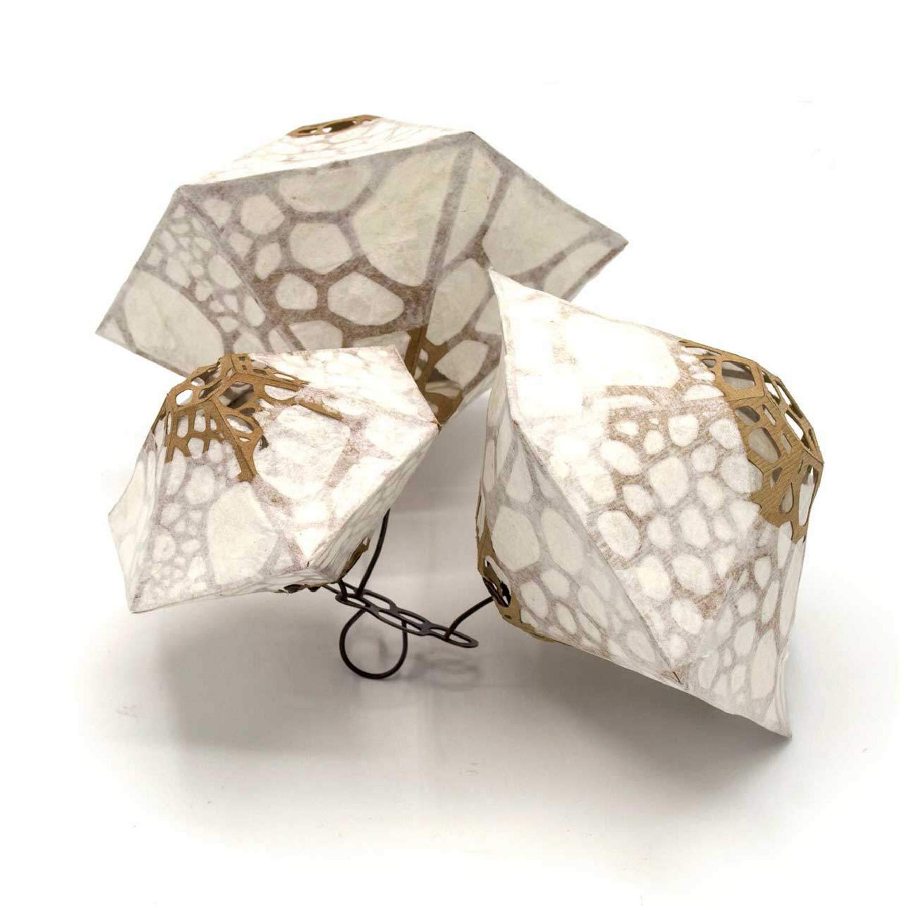 Student work: faceted geometric forms in transluscent paper with brown web-like pattern underneath