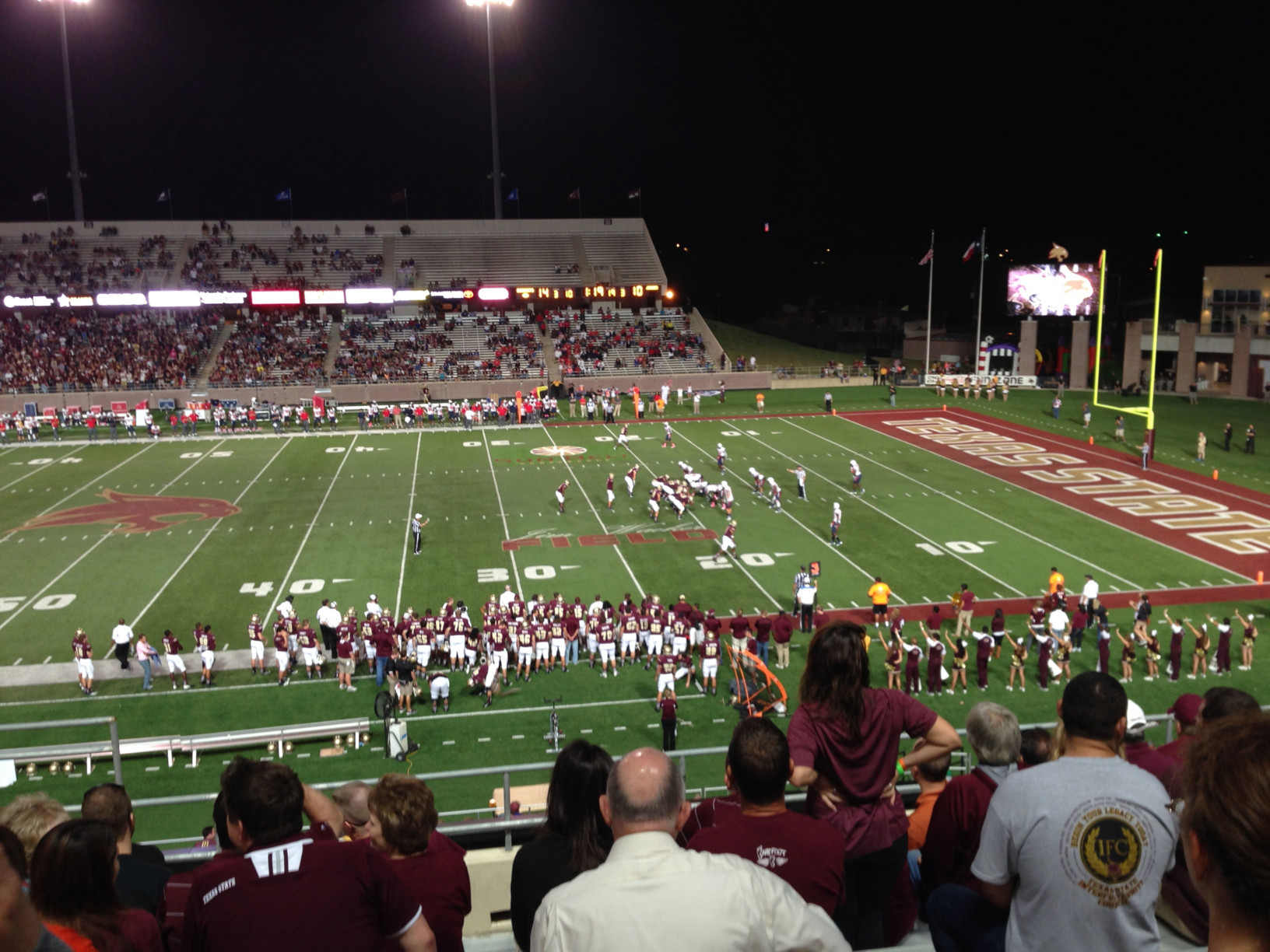 A crowd watches a homecoming Texas State football game.