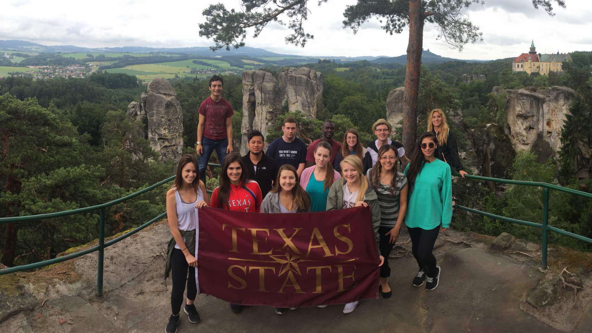 Students posing with Texas State University flag on a study abroad trip