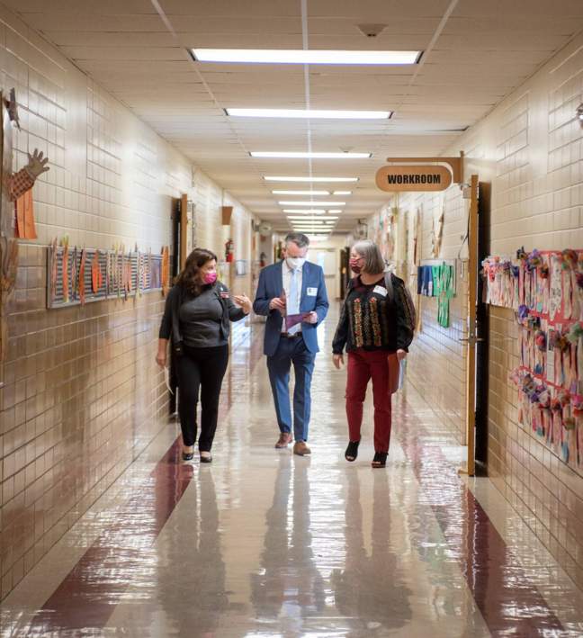three people walking through school hallway