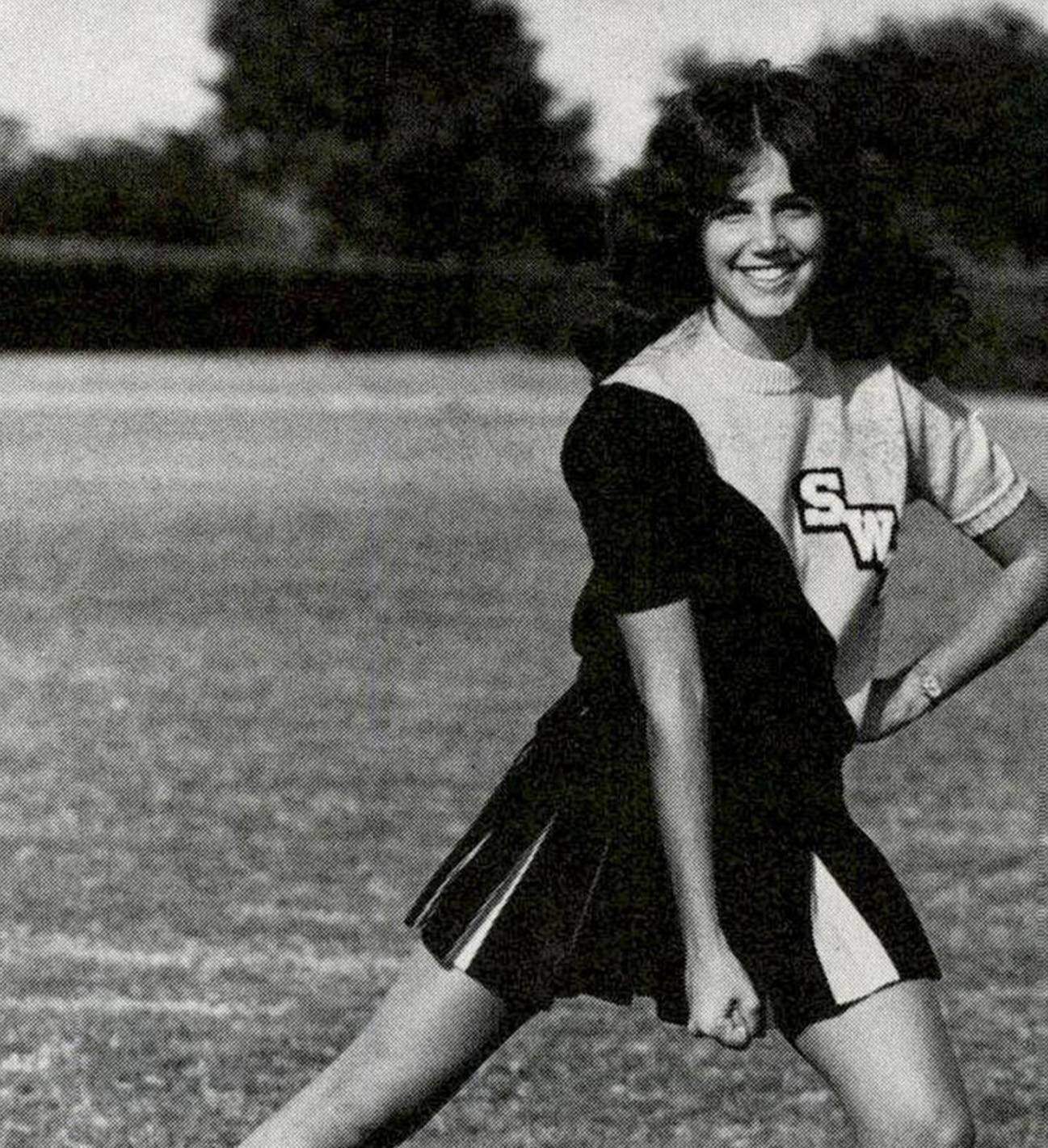 black and white photo of cheerleader on football field